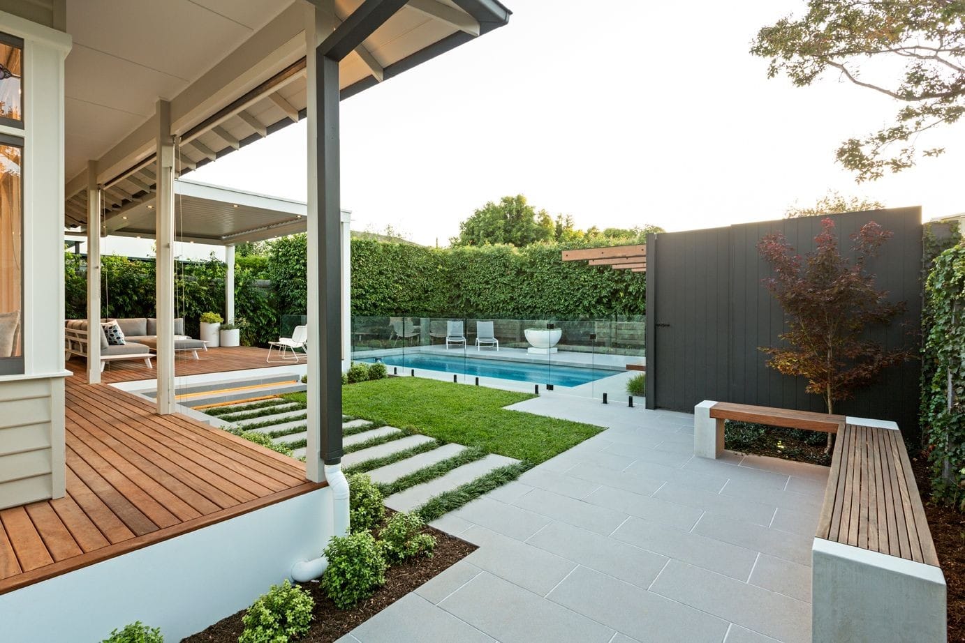 Paved entertaining area with a decked alfresco, formal lawn and family pool in Melbourne.