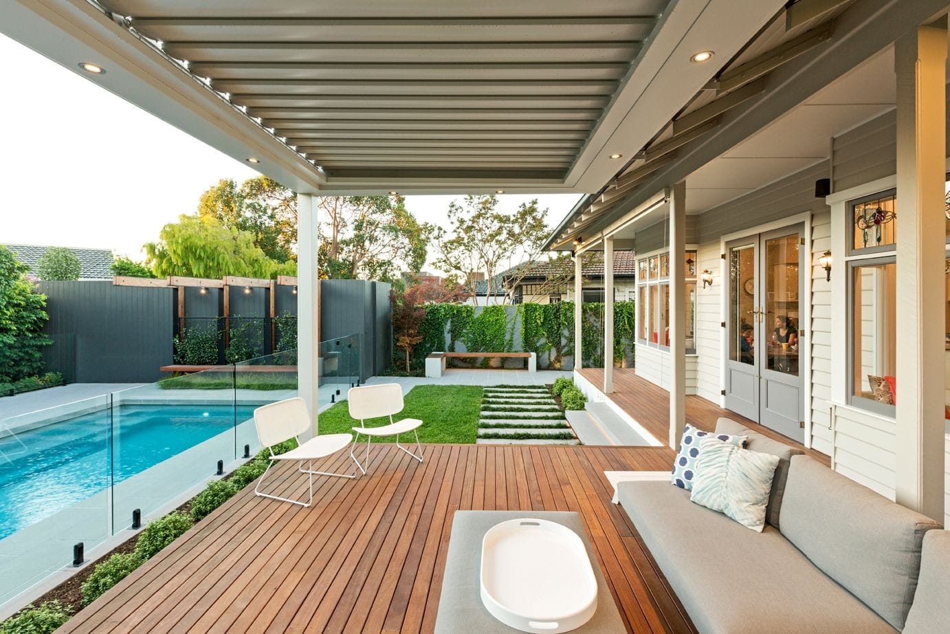 Alfesco decking with a louvred roof overlooks a stunning backyard in Melbourne.